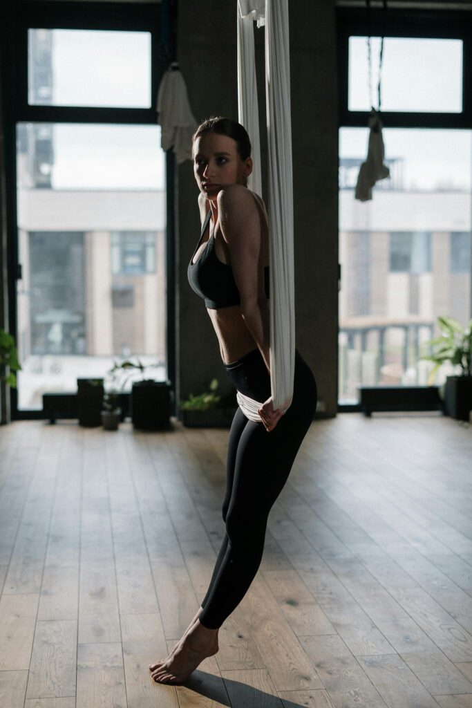 Woman practicing aerial yoga in a studio setting, focusing on balance and wellness.