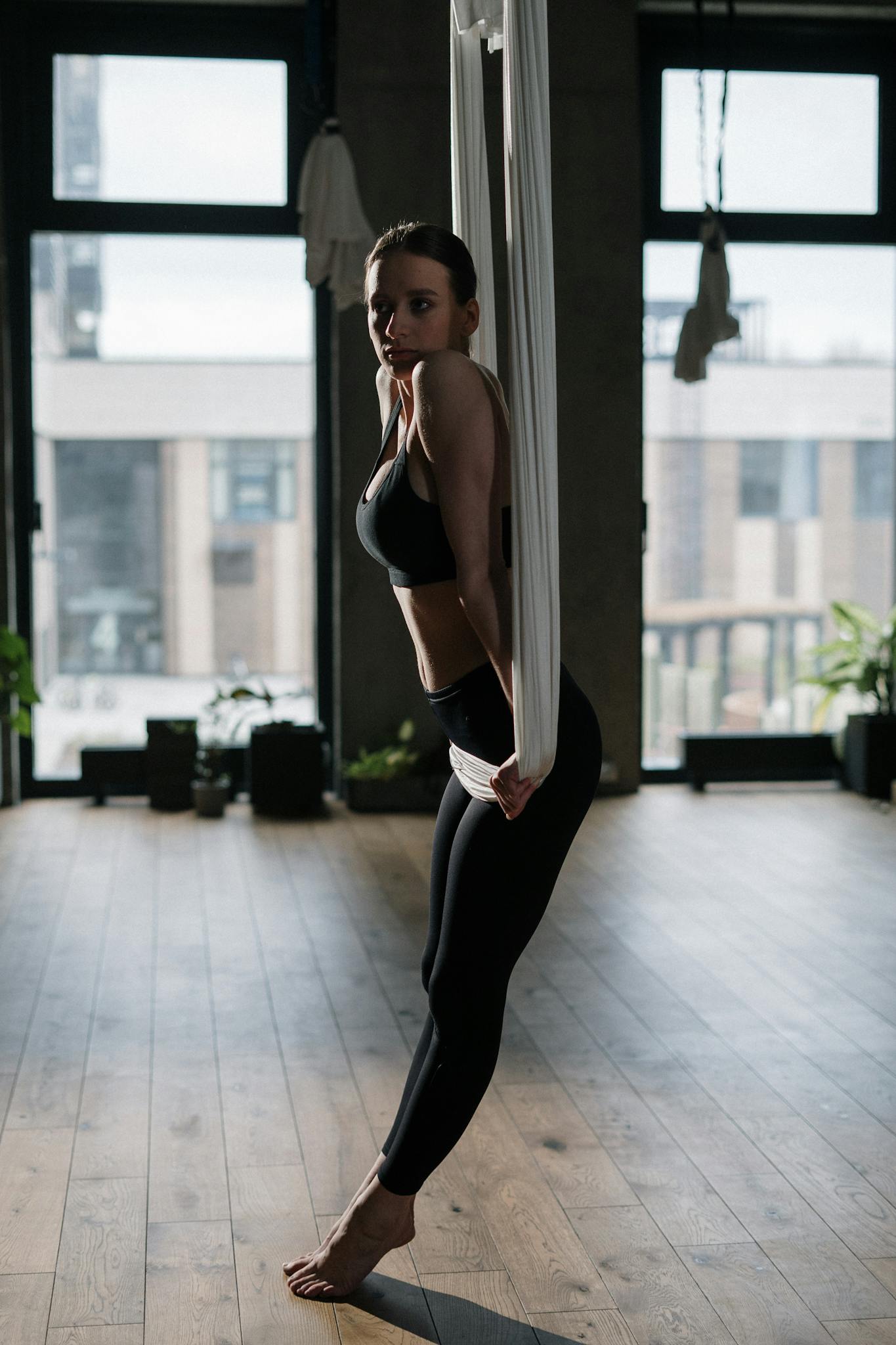 Woman practicing aerial yoga in a studio setting, focusing on balance and wellness.