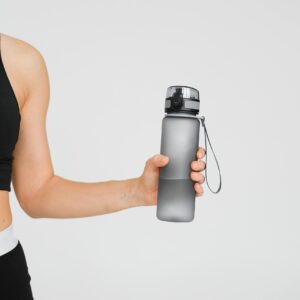 Close-up of an athletic woman holding a water bottle, focusing on fitness and hydration.